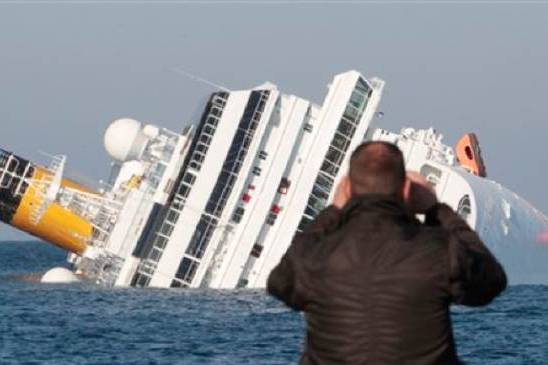 A person takes a picture of the submerged cruise ship off Giglio Island.